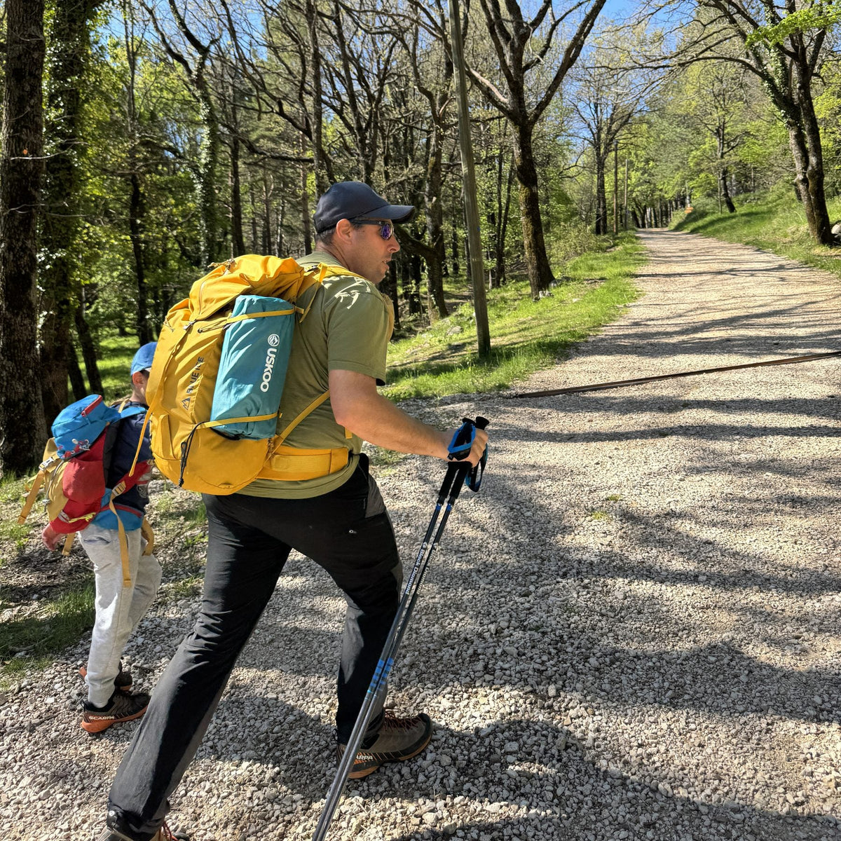 A parent and child on a forest trail, a packed AirFlex strapped to the side of the backpack.