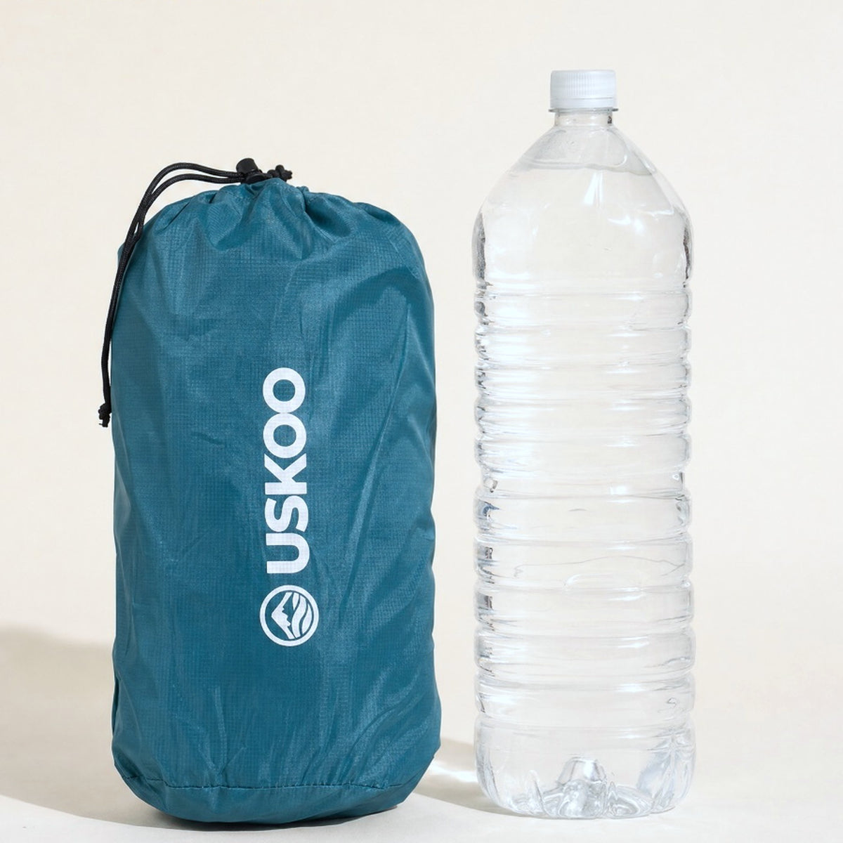 Uskoo AirFlex packed in its stuff sack next to a 2-liter water bottle for scale Image