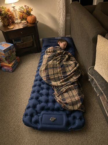 Customer photo: child asleep under a blanket on a navy Uskoo AirFlex pad in a living room