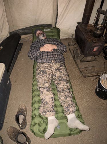 Customer photo: tall camper lying full length on a green Uskoo AirFlex pad in a canvas tent