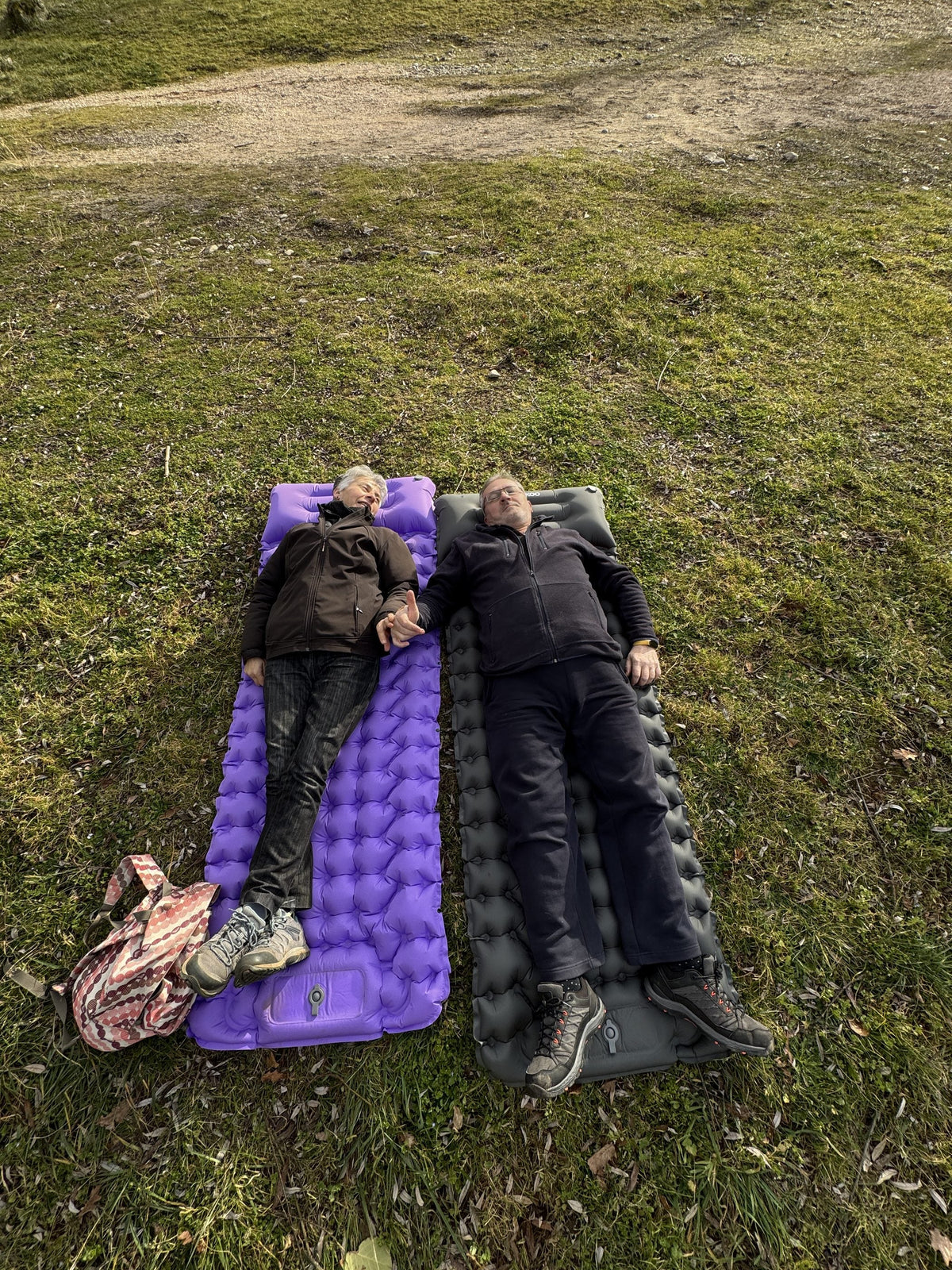 A couple stretched out on two AirFlex pads in the grass